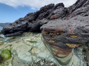 ②赤茶けた鍰と緑泥片岩の岩礁
